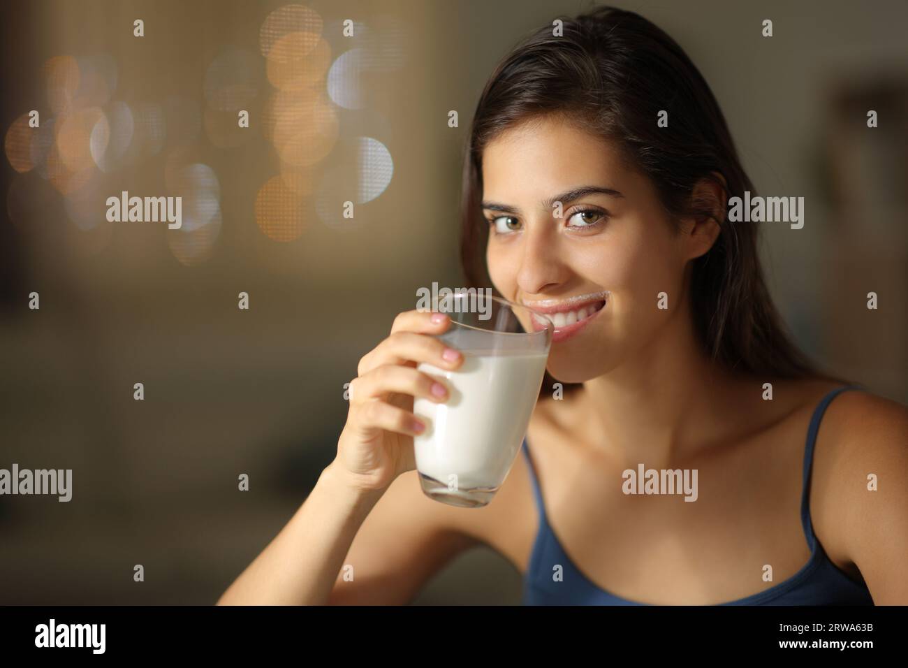 Happy woman drinking milk looking at camera in the night at home Stock Photo