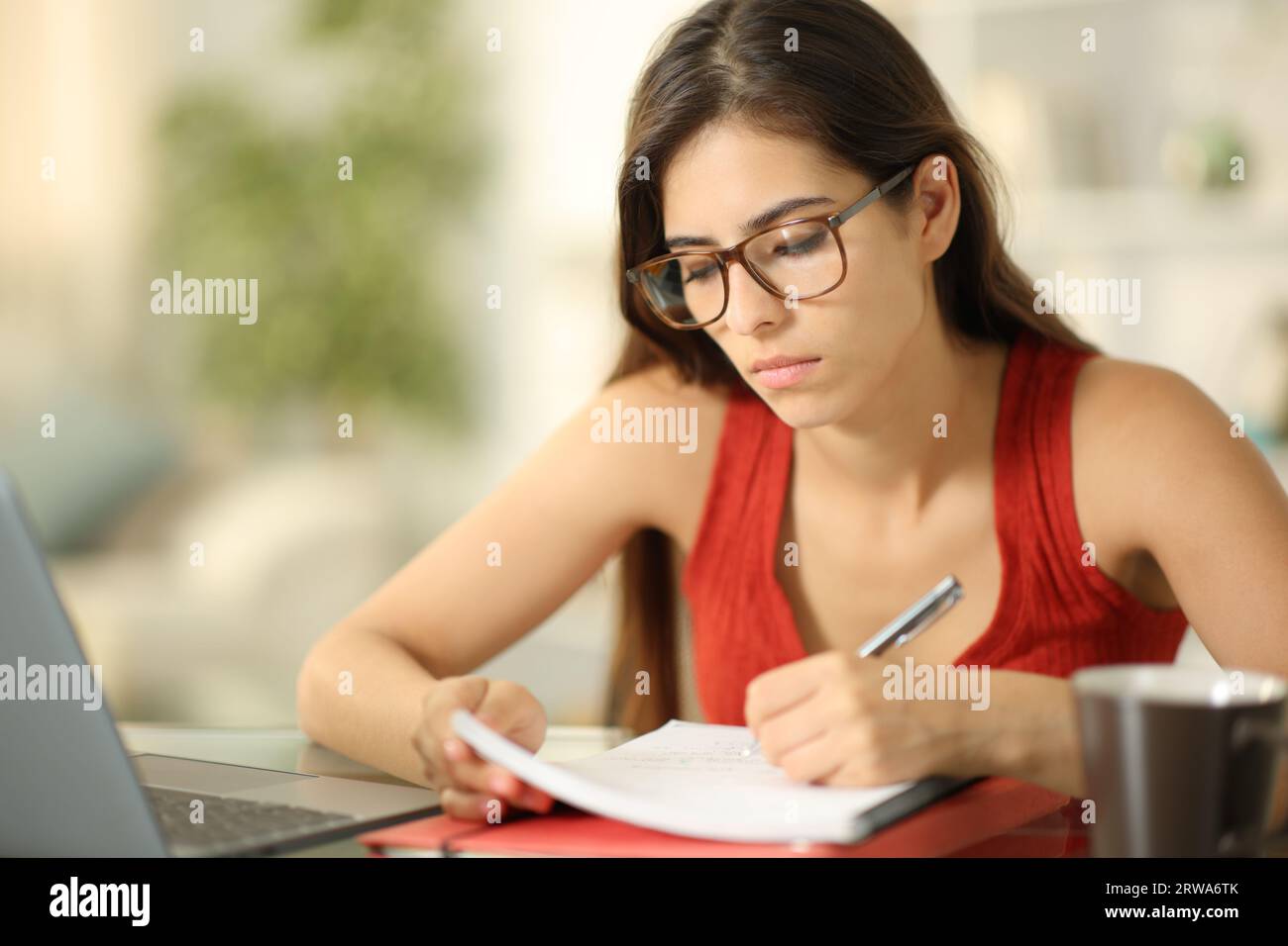 Student wearing glasses taking notes at home Stock Photo