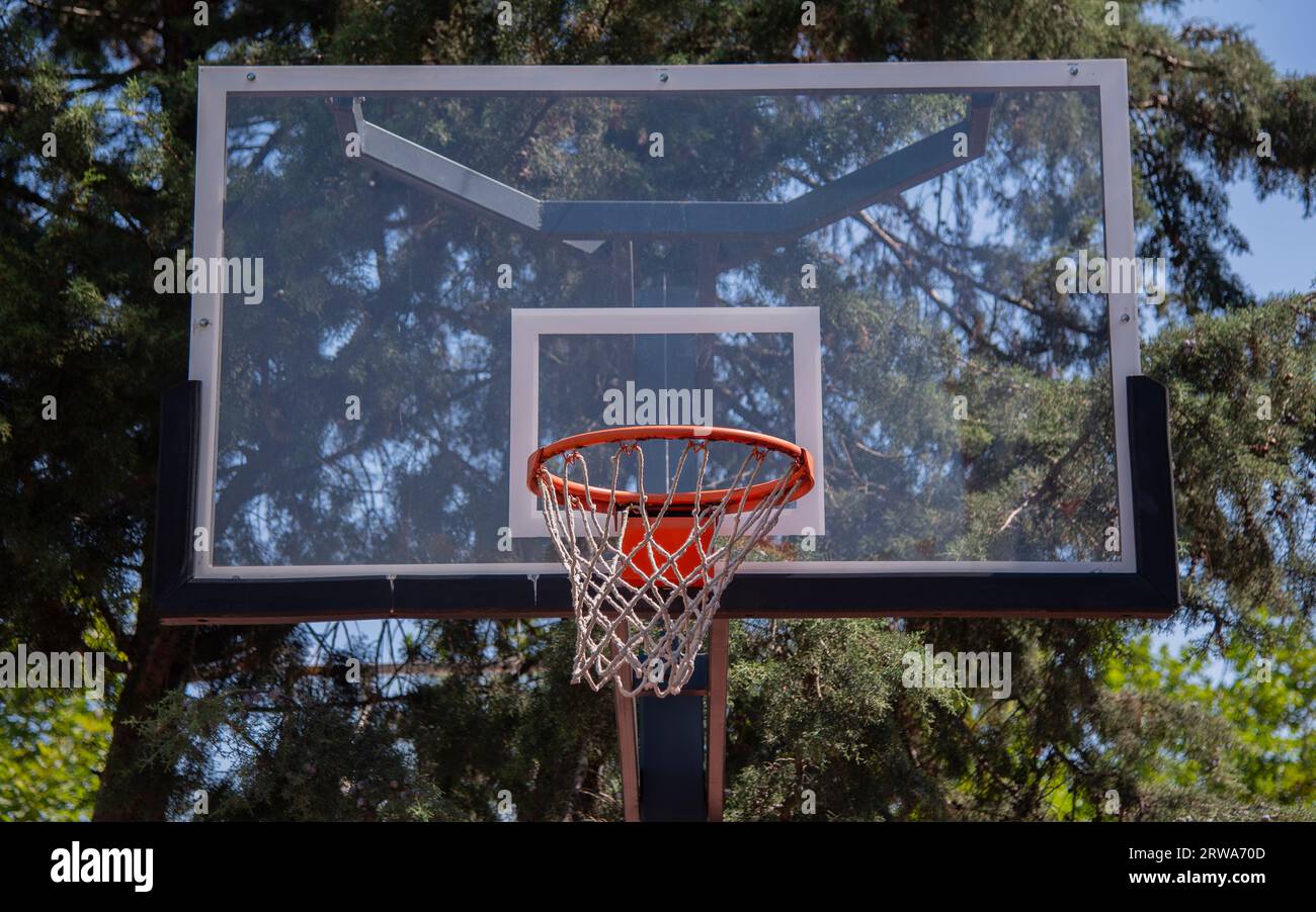 Basketball court outdoors, orange hoop, net and backboard for basket
