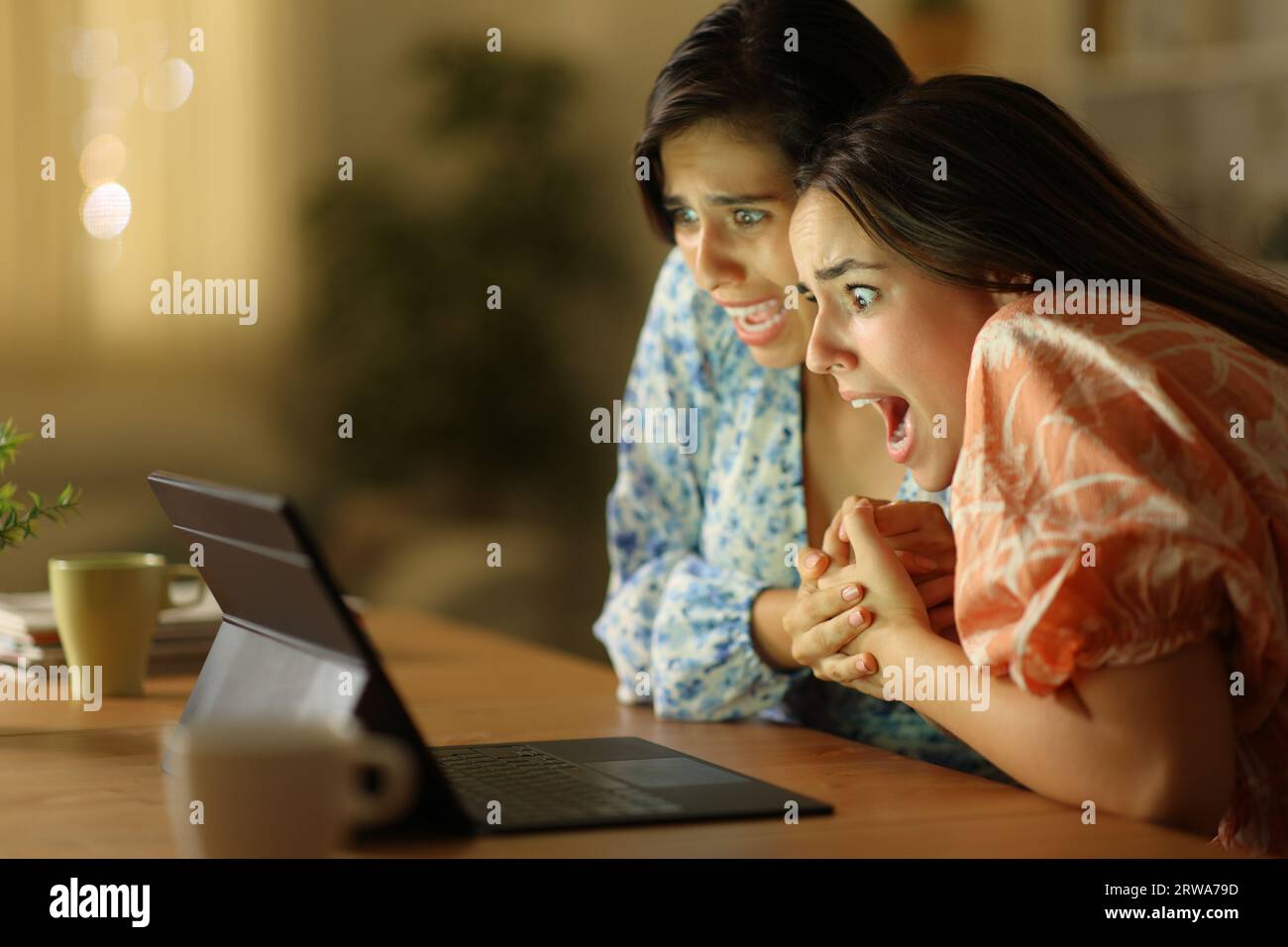 Terrified women watching media on laptop in the night at home Stock Photo