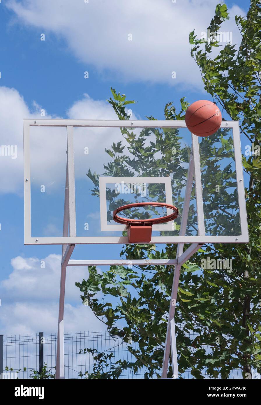 Basketball court outdoors, orange hoop, net and backboard for basket