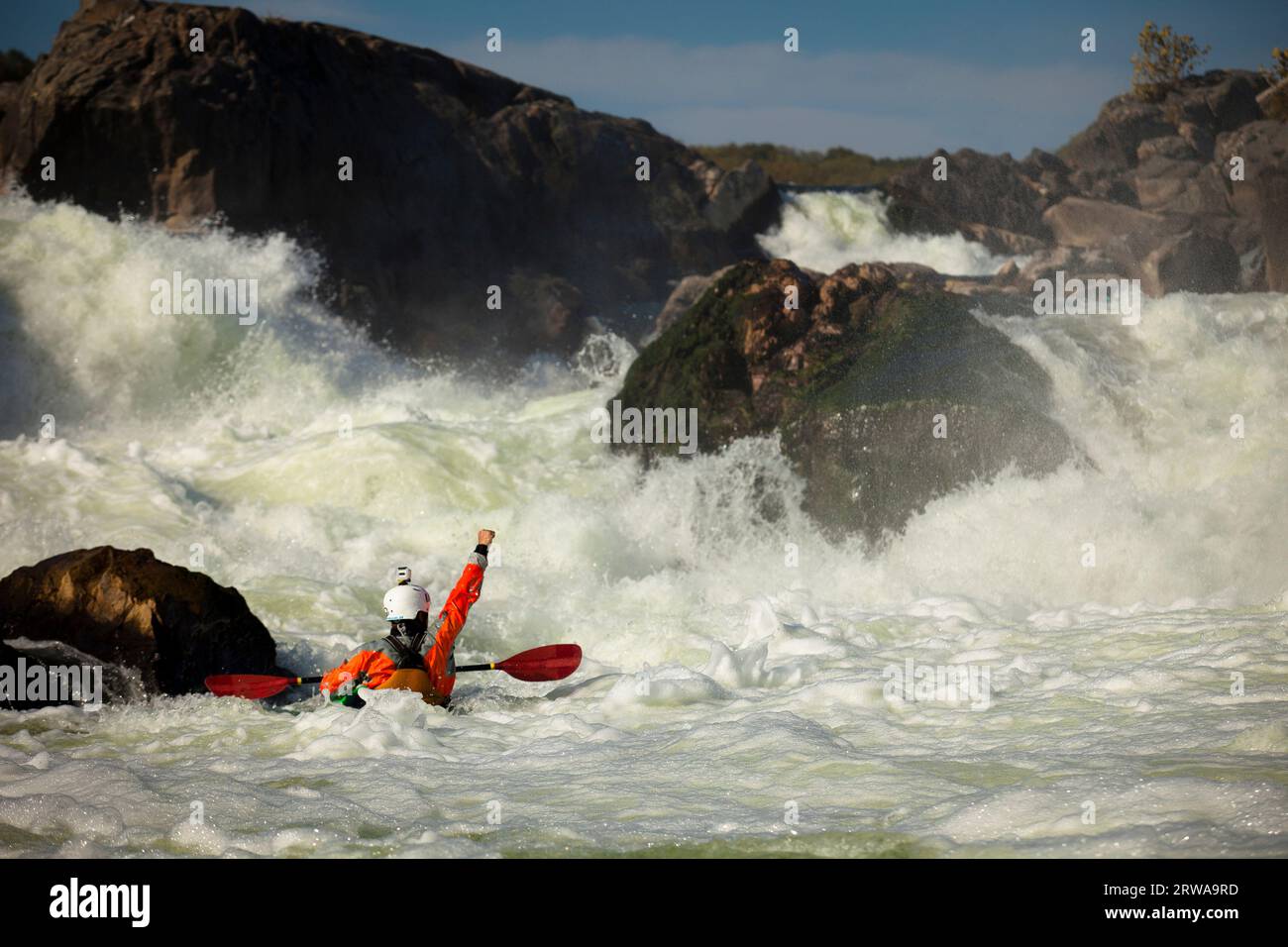 Professional whitewater kayaker Clay Lucas in an orange dry top celebrates a clean descent of a rapid in the Great Falls section of the Potomac River Stock Photo