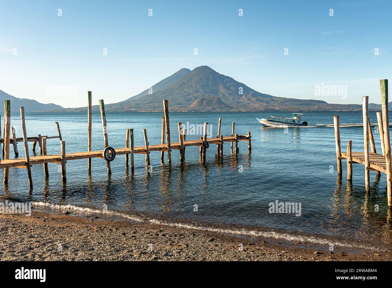 Wooden docks on Lake Atitlan on the beach in Panajachel, Guatemala. With Toliman and San Pedro volcanoes in the background. A beautiful bay of lake wi Stock Photo