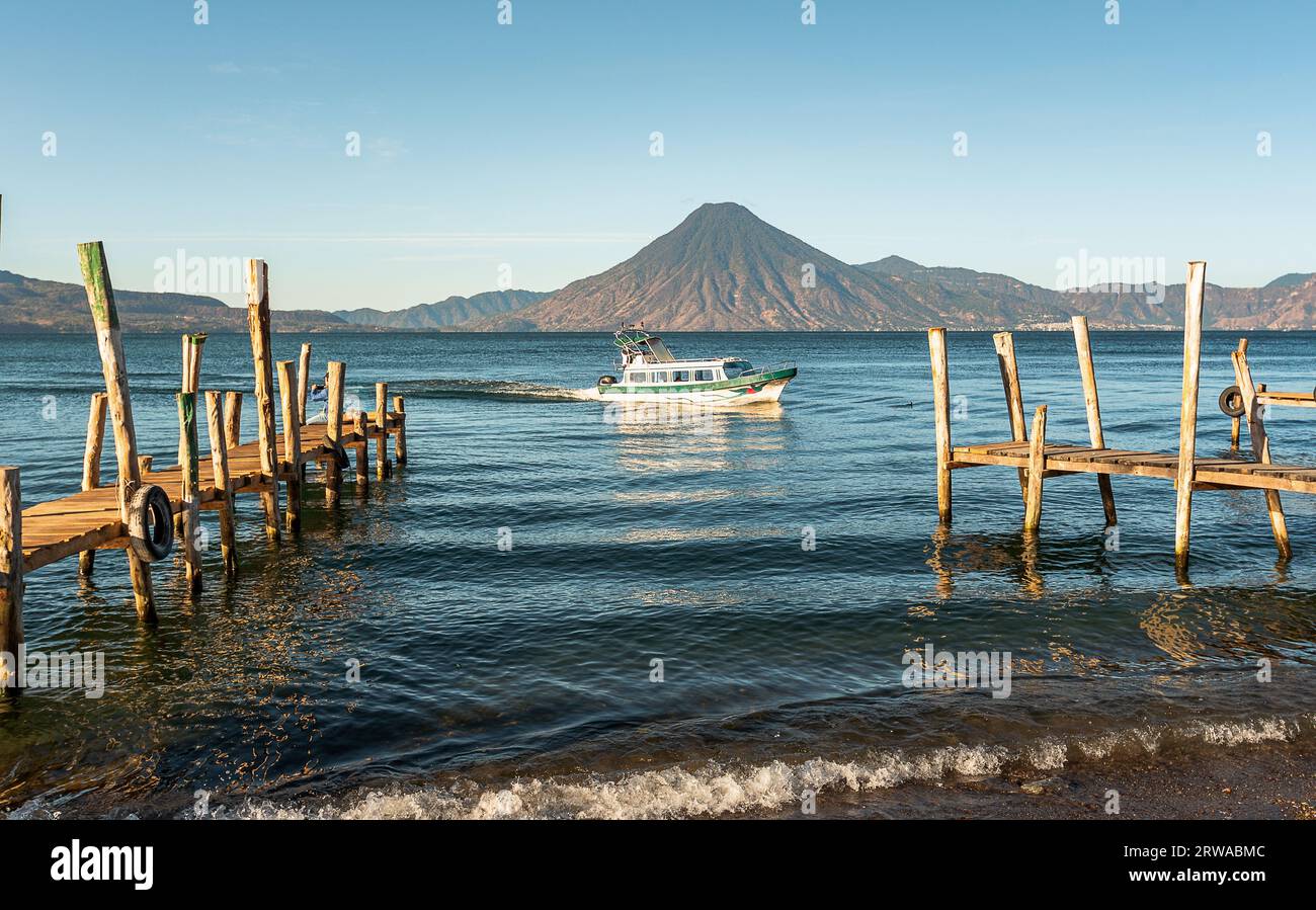 Wooden docks on Lake Atitlan on the beach in Panajachel, Guatemala. With Toliman and San Pedro volcanoes in the background. A beautiful bay of lake wi Stock Photo