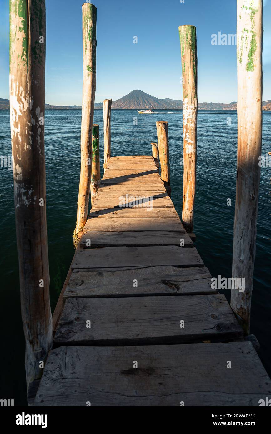 Wooden dock on Lake Atitlan on the beach in Panajachel, Guatemala. With Toliman and San Pedro volcanoes in the background. A beautiful bay of lake wit Stock Photo