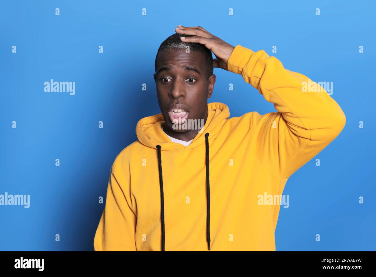 Confused black guy touching his head, blue background Stock Photo