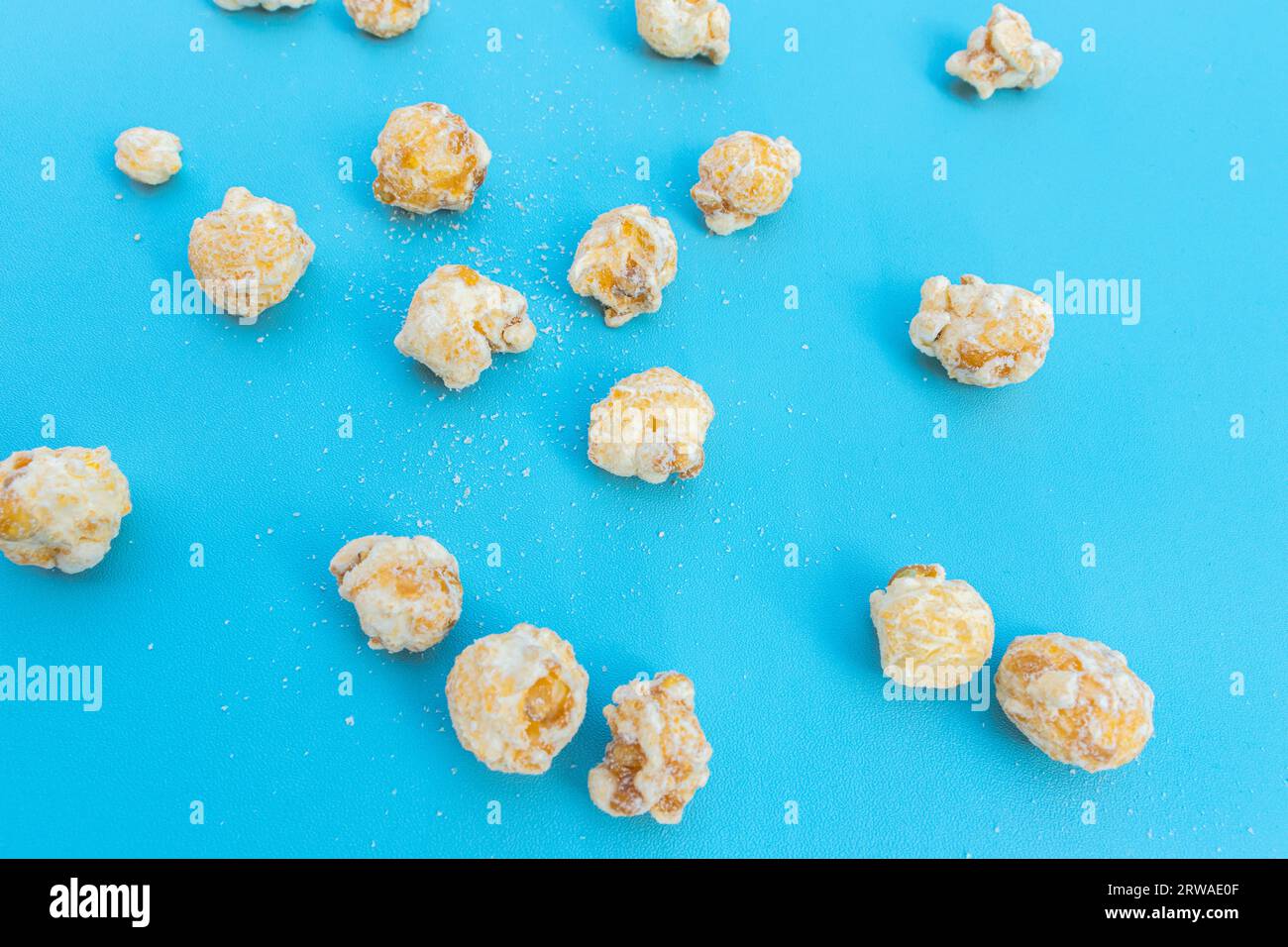 Popcorn scattered on blue background, after some edits. Stock Photo