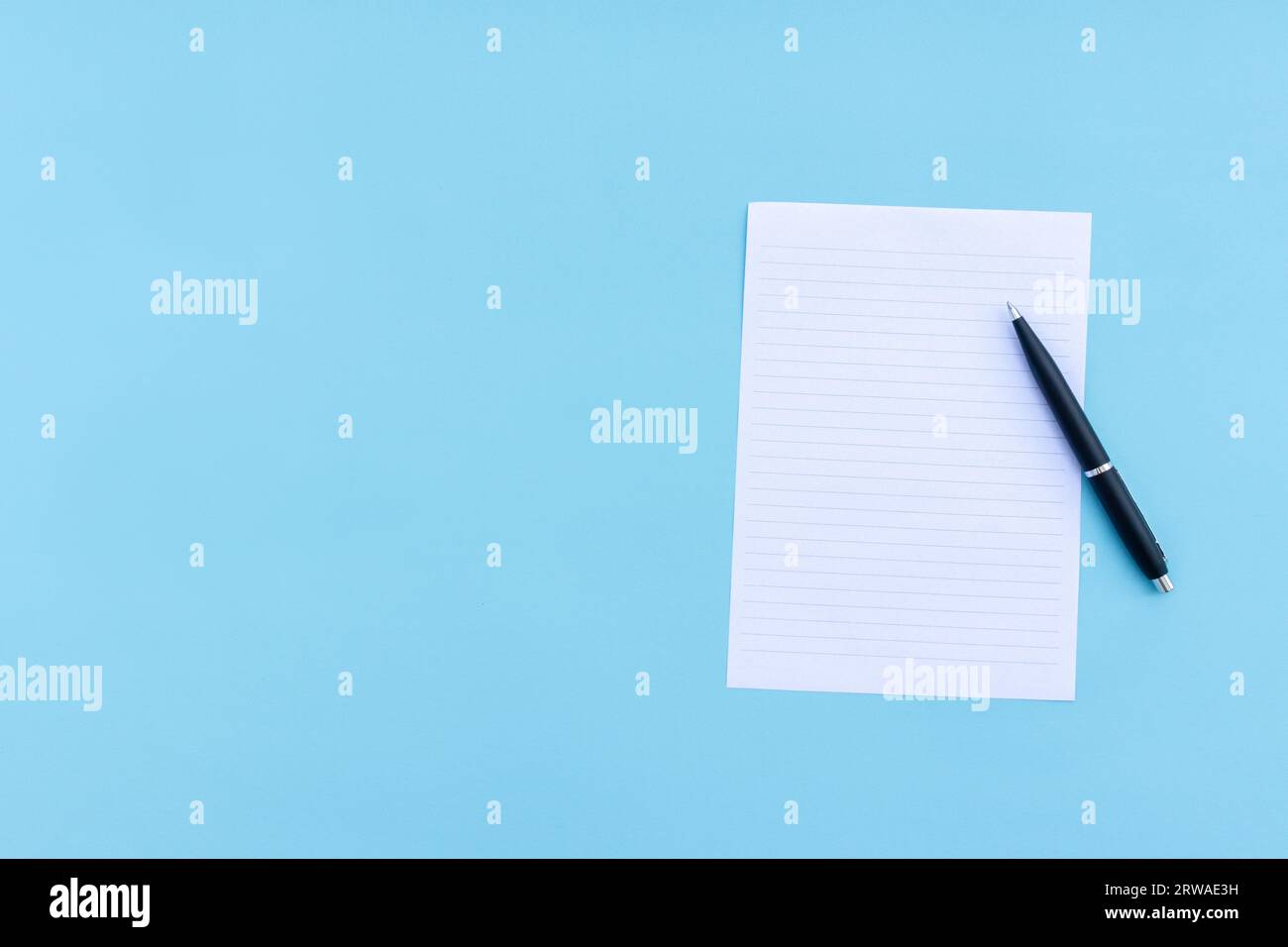 Blank white paper and pen isolated on blue background. After some edits. Stock Photo
