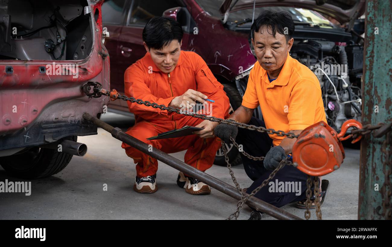 Mechanic testing strength and reliability of chain hoist for car towing