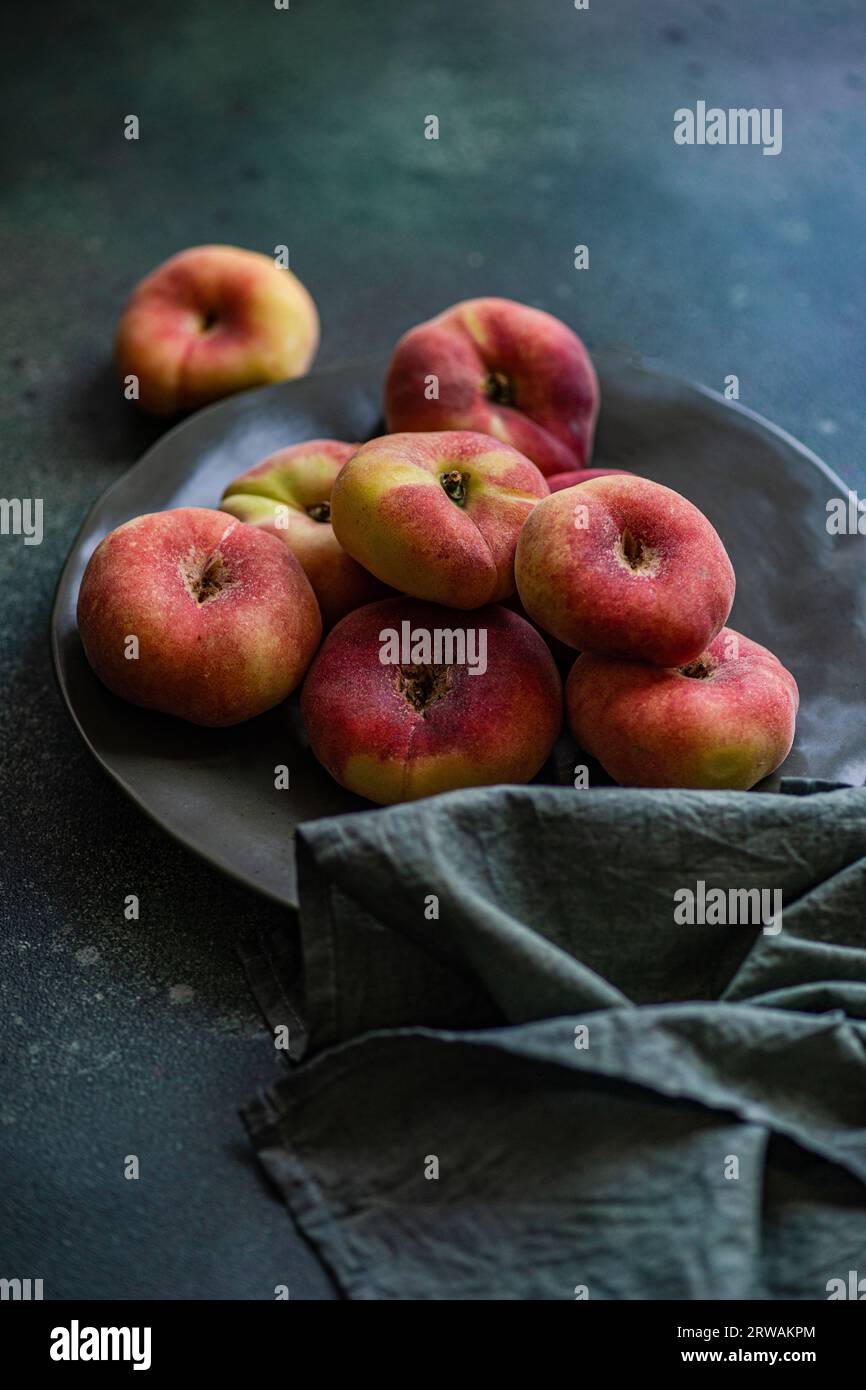 Zodiac peach fruits on the plate on dark green concrete background Stock Photo