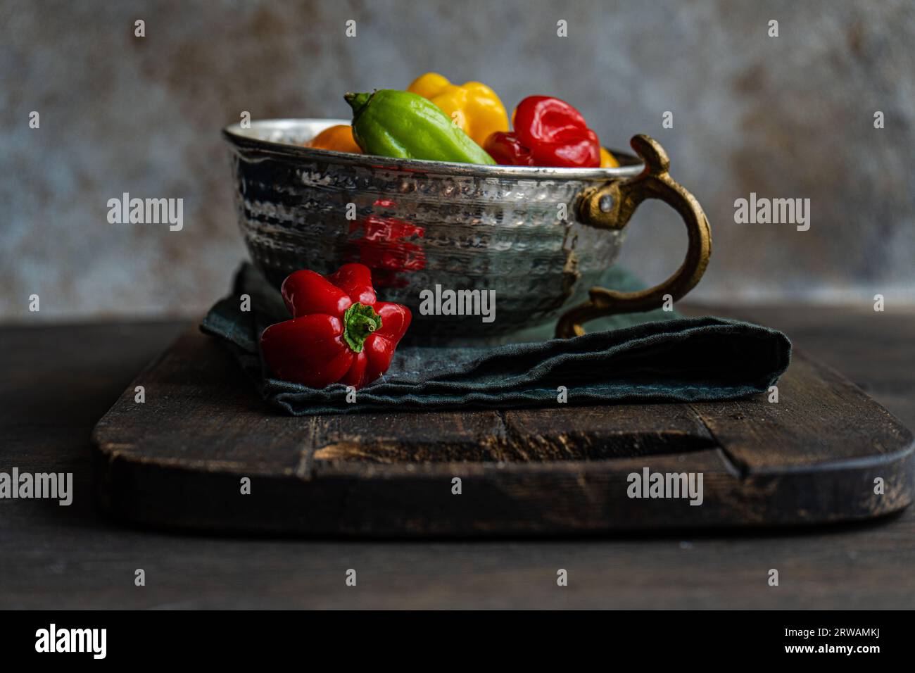 Vintage metal bowl with colorful Scotch Bennet peppers on wooden table Stock Photo
