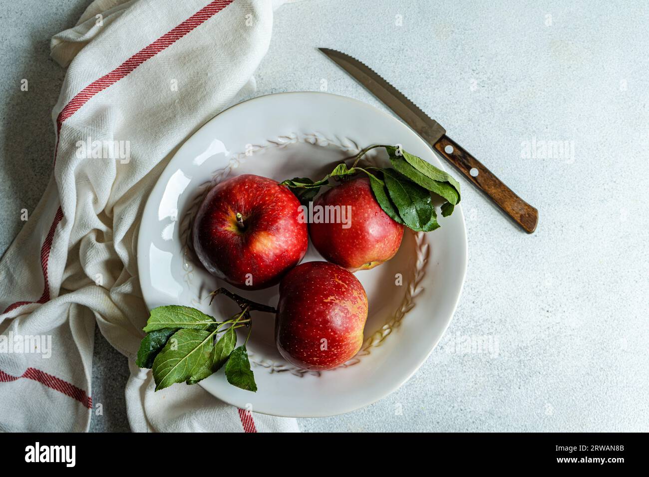 Overhead view of three ripe red apples on a plate Stock Photo