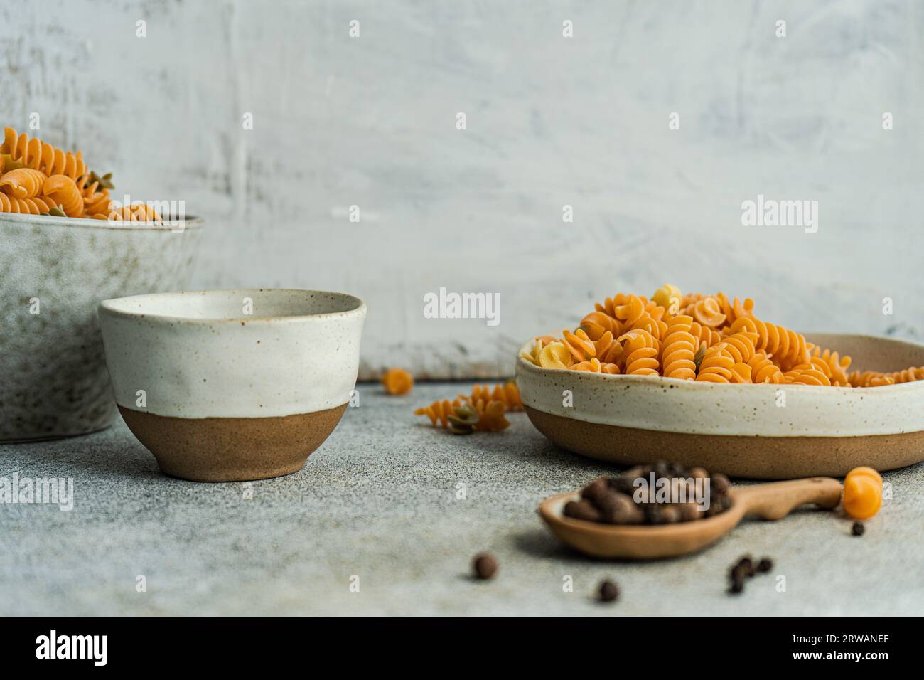 Colorful vegetarian fussili pasta in the bowls on concrete table Stock Photo