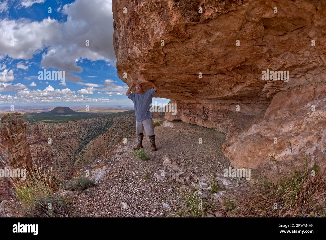 A hiker standing under a cliff overhang below Desert View Point at Grand Canyon South Rim Arizona. Stock Photo