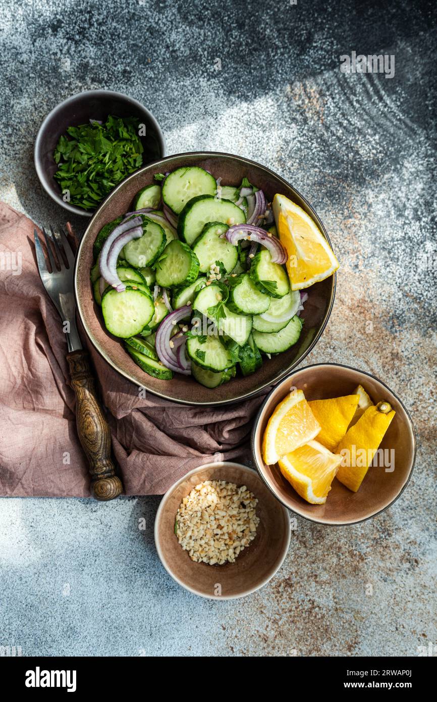 Overhead view of a cucumber and red onion salad with chopped nuts, herbs and lemon Stock Photo