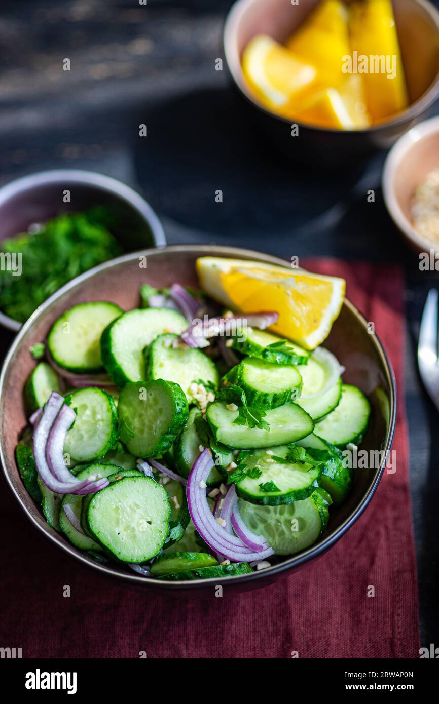 Healthy cucumber salad with chopped nuts and lemon seved in the bowl Stock Photo