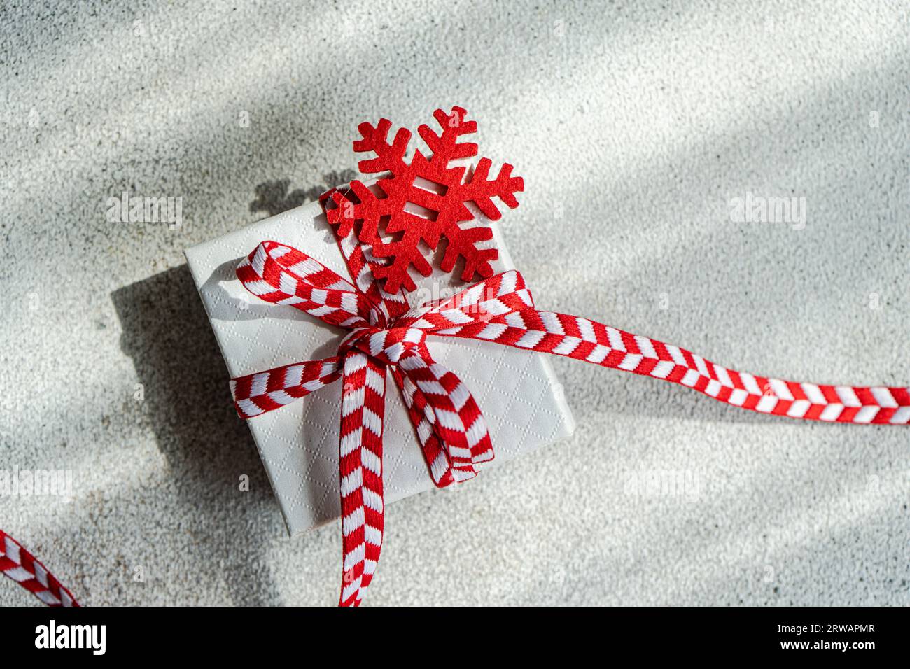 Overhead view of a gift box tied with a ribbon and snowflake ornament Stock Photo