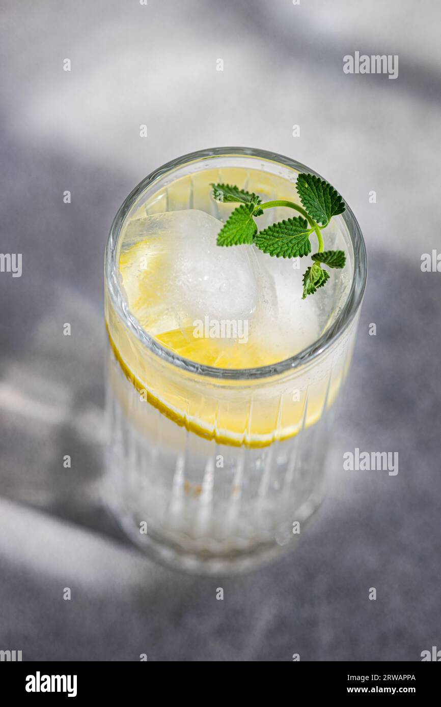 Cocktail of tonic and vodka served with lemon and mint in crystal glass in sunny day Stock Photo