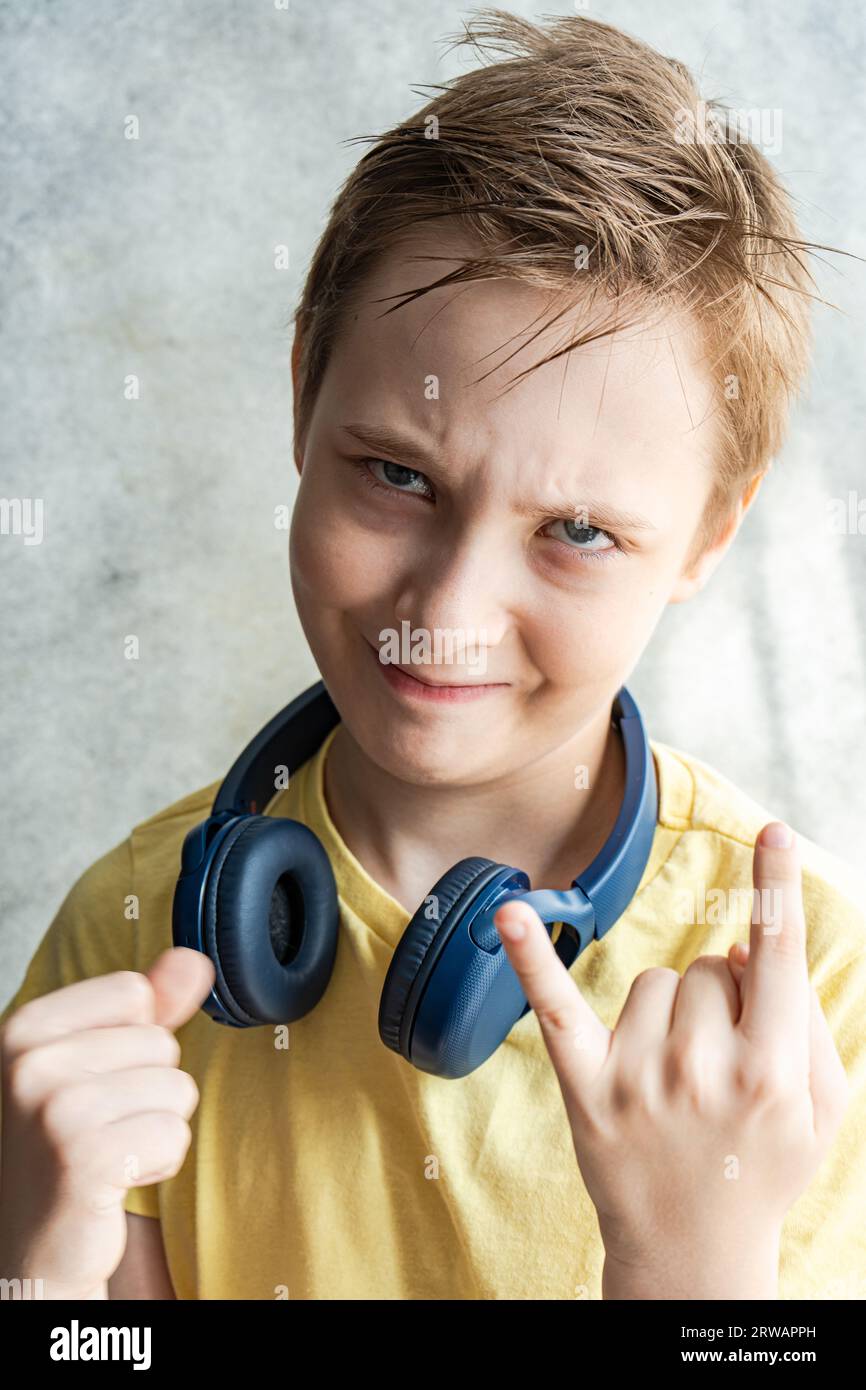 Portrait of a boy with headphones around his neck making a horn sign with his hand Stock Photo
