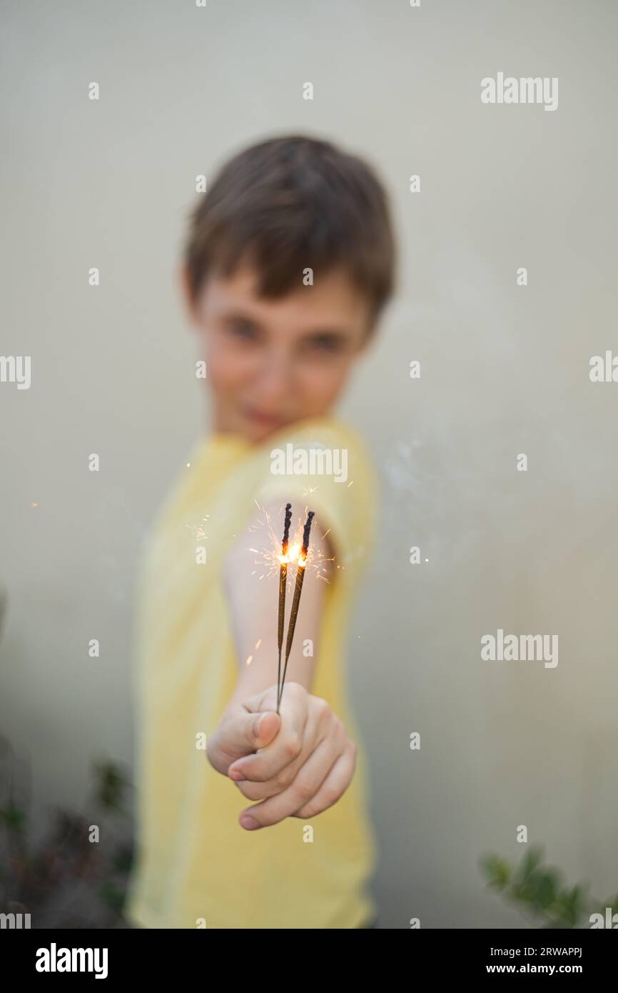 Portrait of a boy standing outdoors holding sparklers Stock Photo