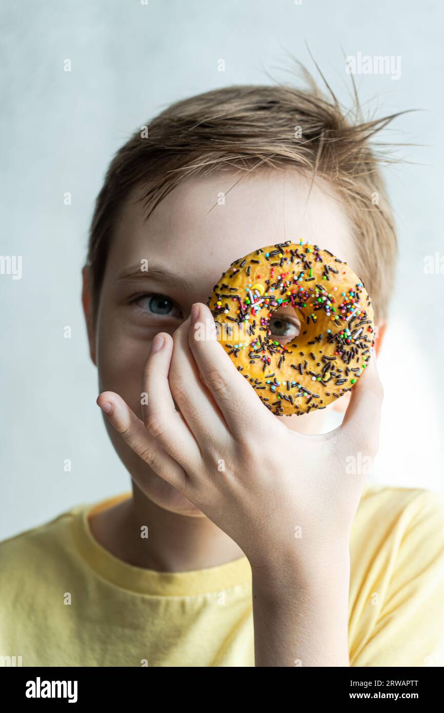 Boy in yellow t-shirt with same color banana donut in the hand Stock Photo