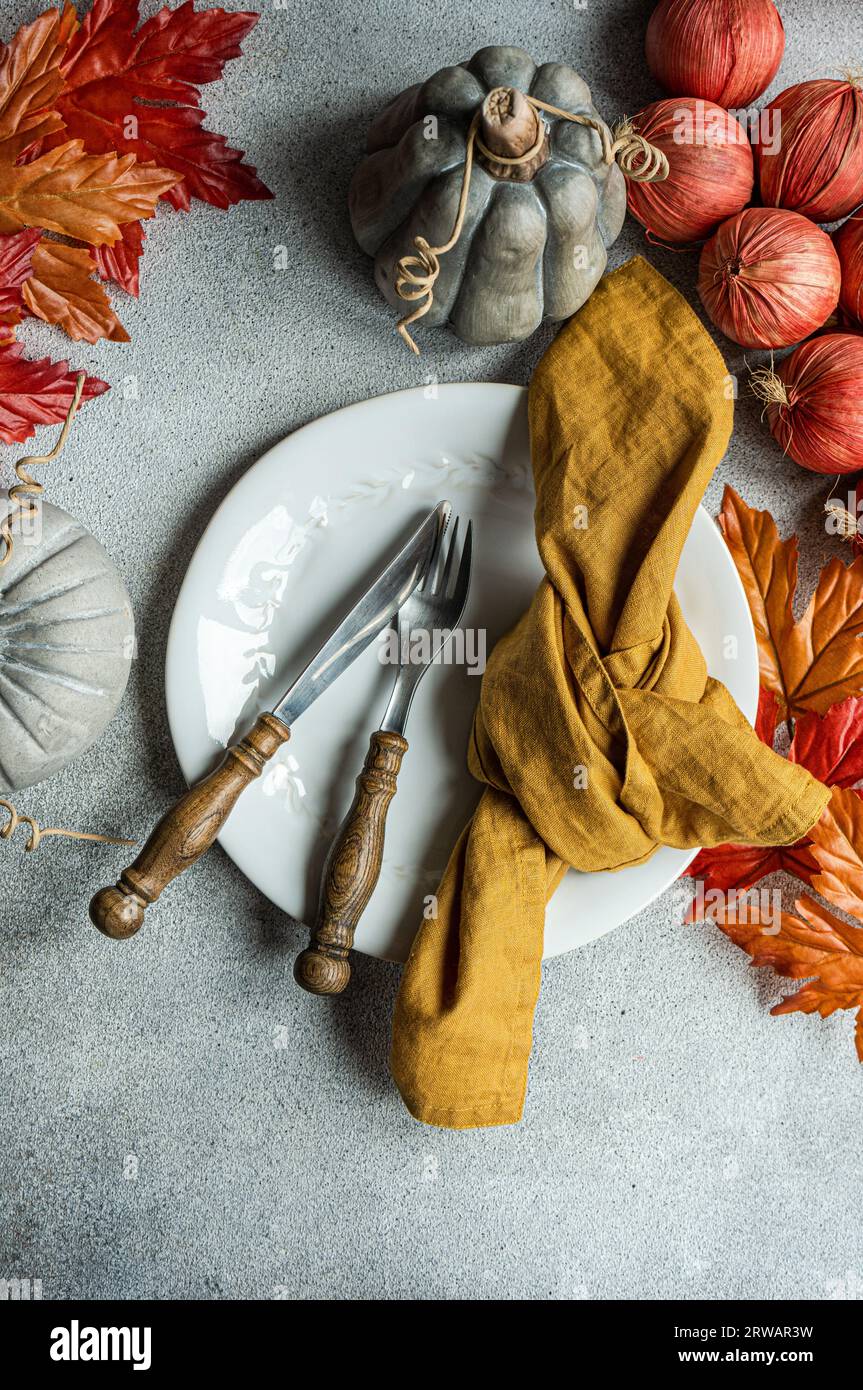 Overhead view off an autumnal place setting with autumn leaves, red onions and pumpkin decorations Stock Photo