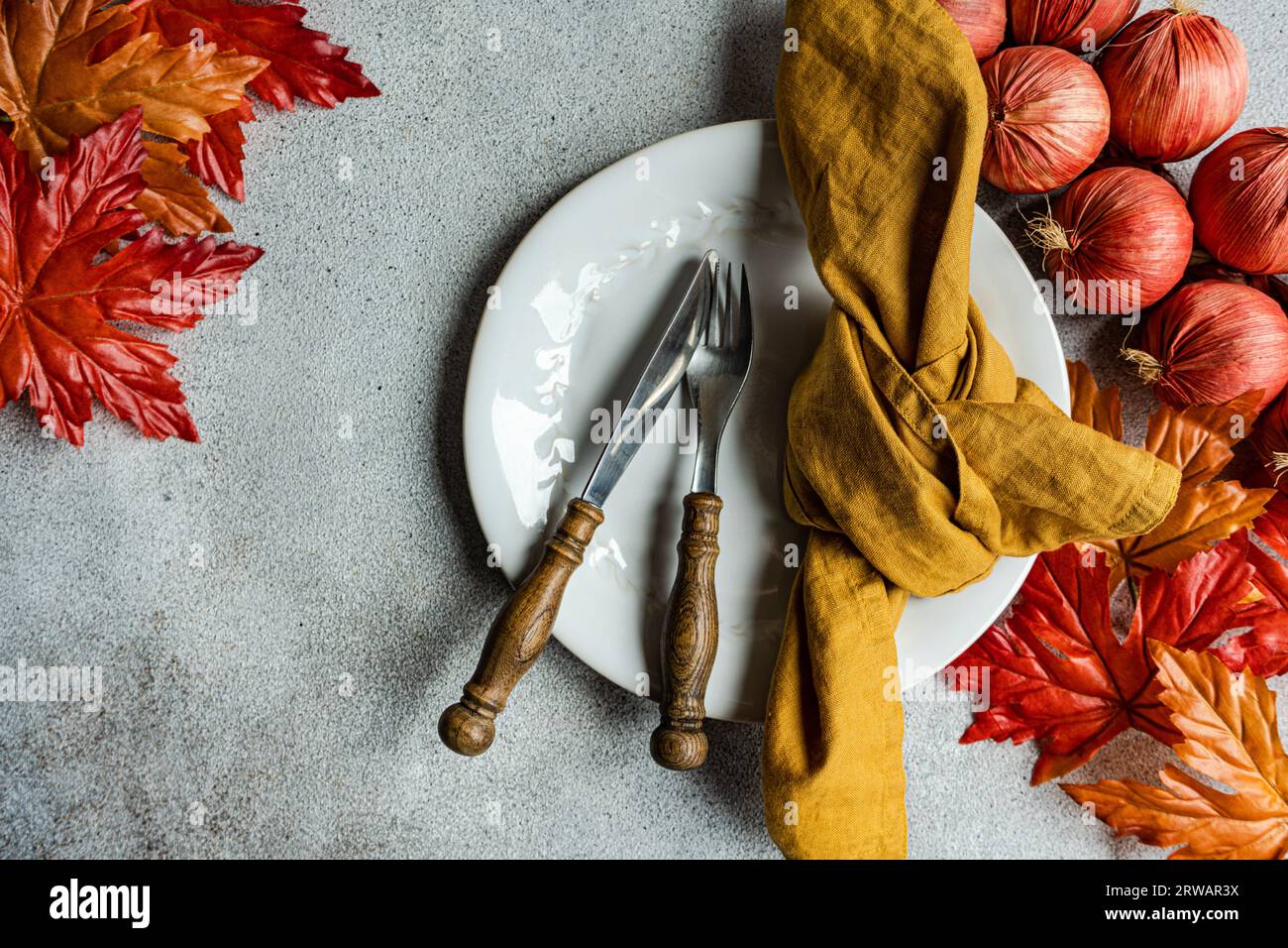 Overhead view off an autumnal place setting with autumn leaves and red onions Stock Photo