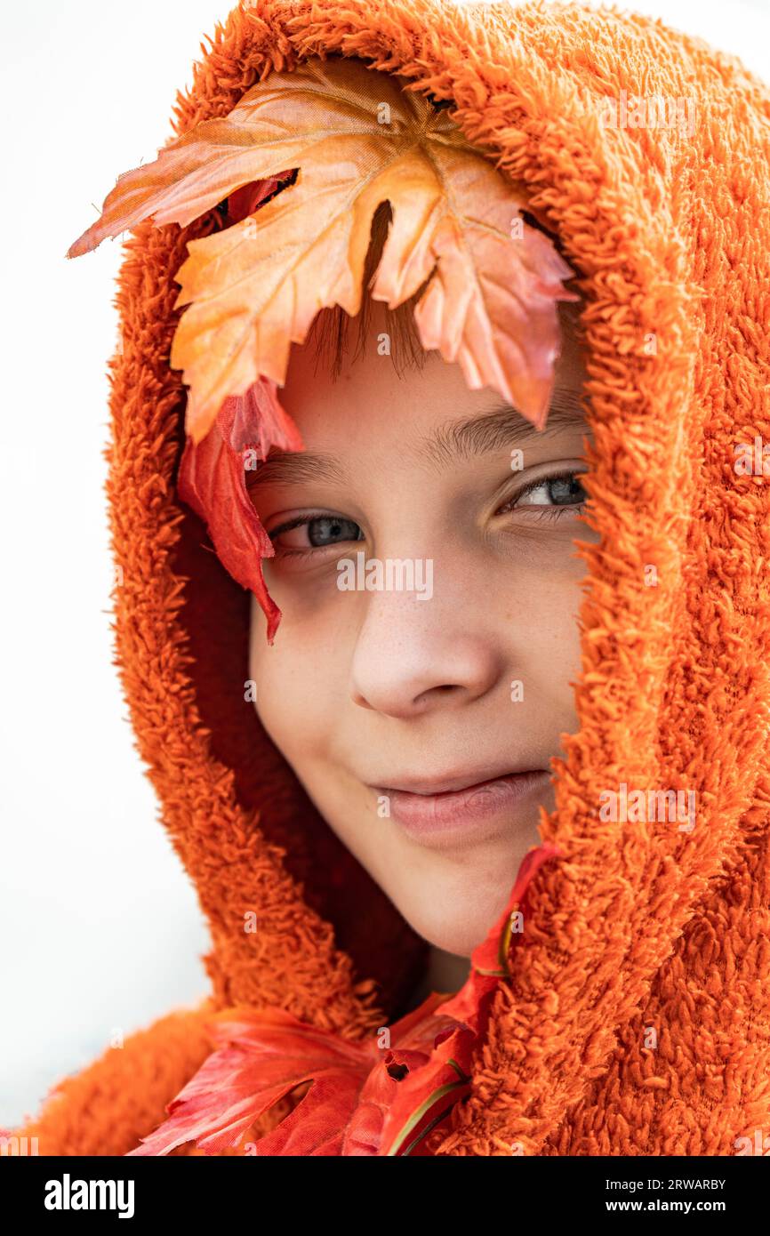 Portrait of a smiling boy with autumn leaves in his orange hoodie Stock Photo