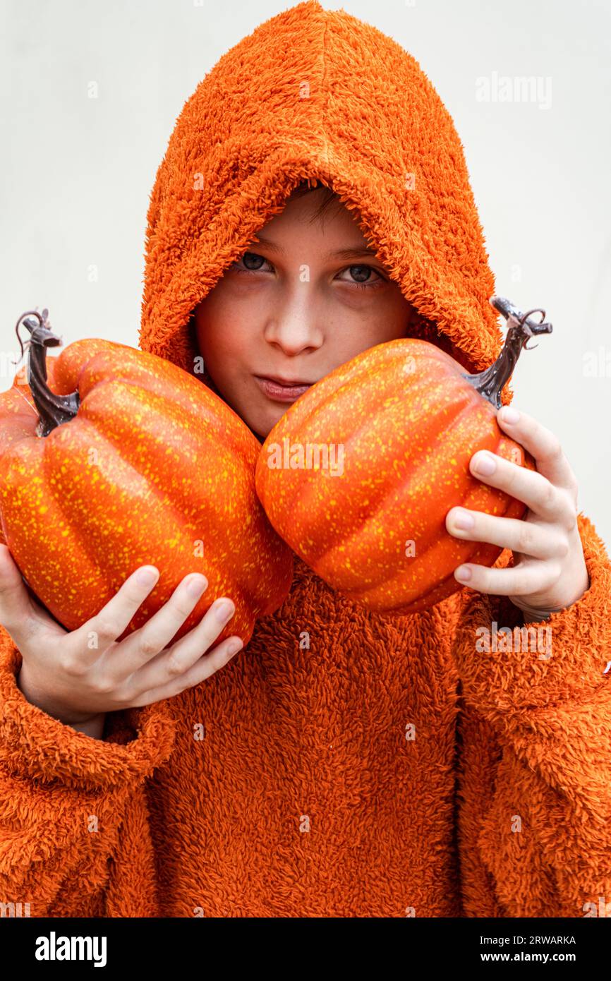 Portrait of a boy holding two pumpkins in front of his face Stock Photo