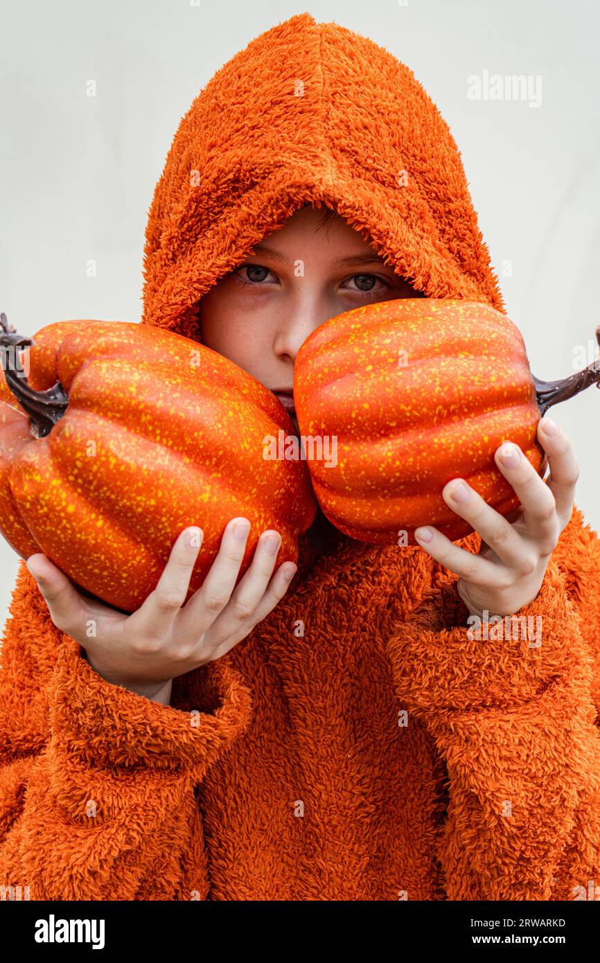 Portrait of a serious boy holding two pumpkins in front of his face Stock Photo