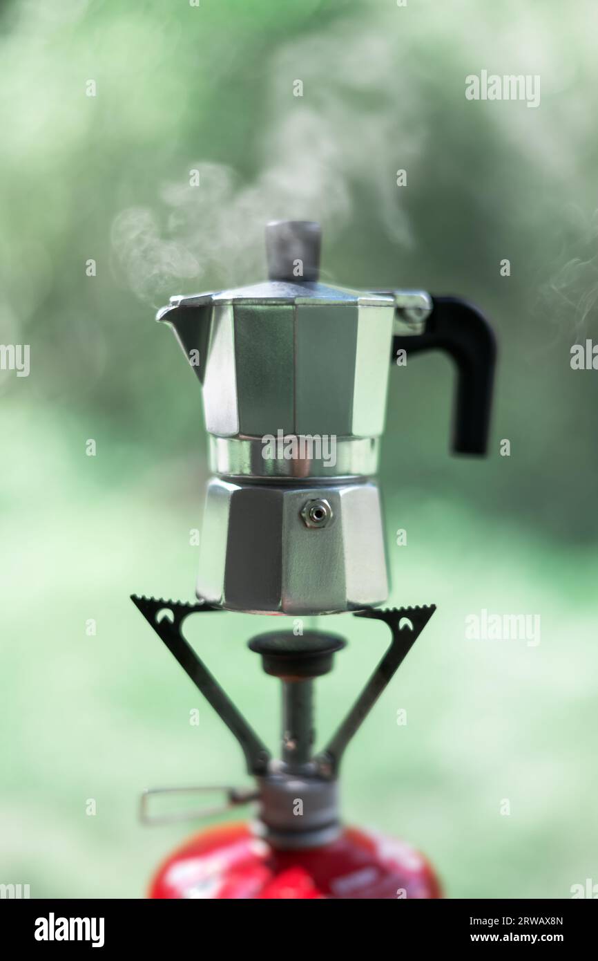 Making coffee outdoors on gas camping fire on small coffee maker Stock Photo