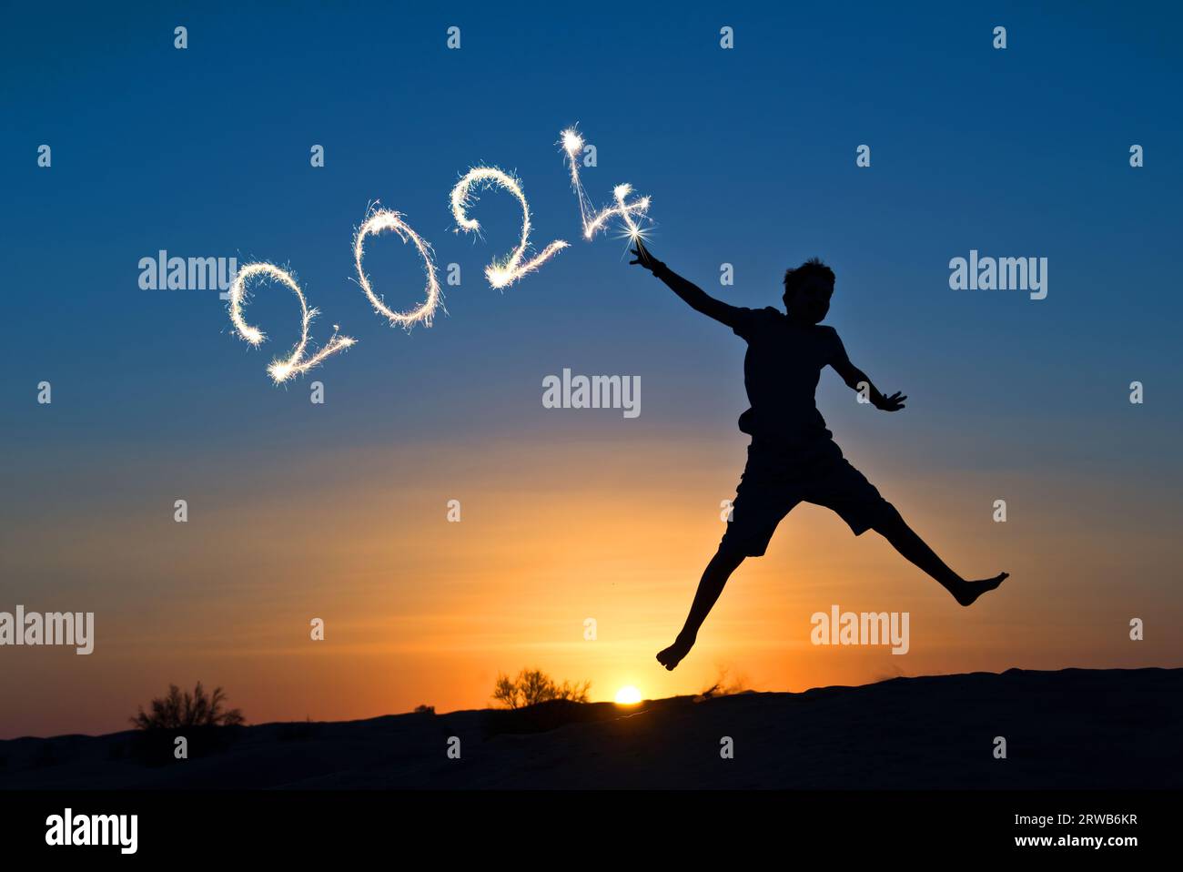 2024 written with sparkles, silhouette of a boy jumping in the sun, new year card Stock Photo
