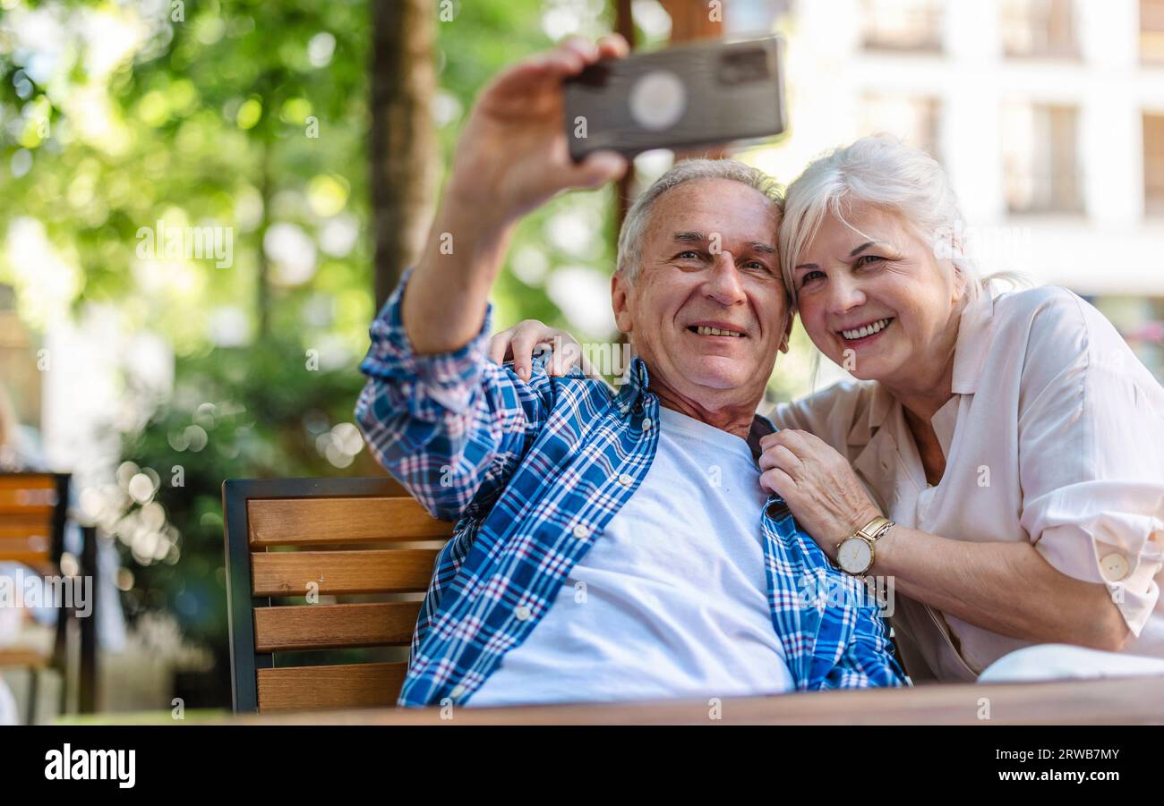 Senior couple sitting at a table in a cafe and using mobile phone Stock Photo