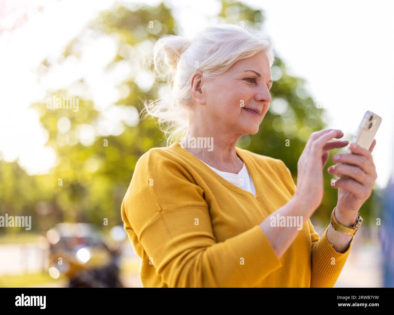 Senior woman using smartphone outdoors Stock Photo