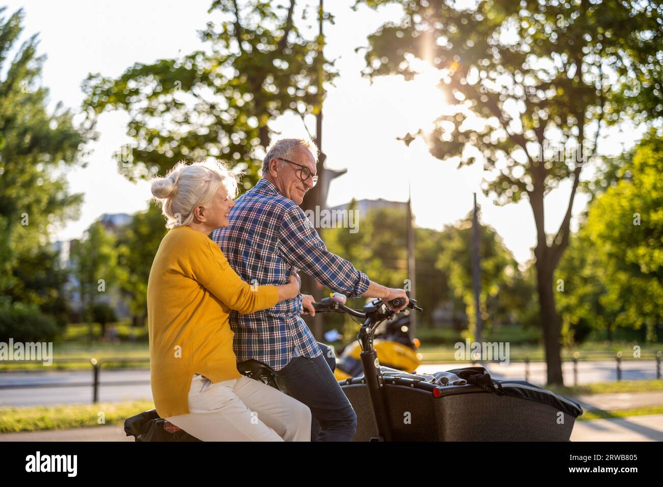 Senior couple riding cargo bike in the city Stock Photo