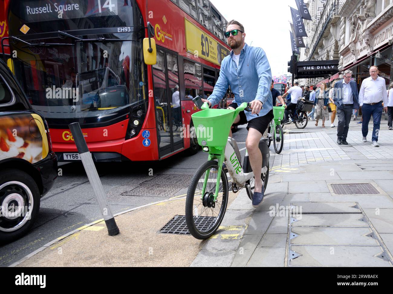 London, England, UK. Man cycling on the pavement in Piccadilly on a Lime rental bike Stock Photo