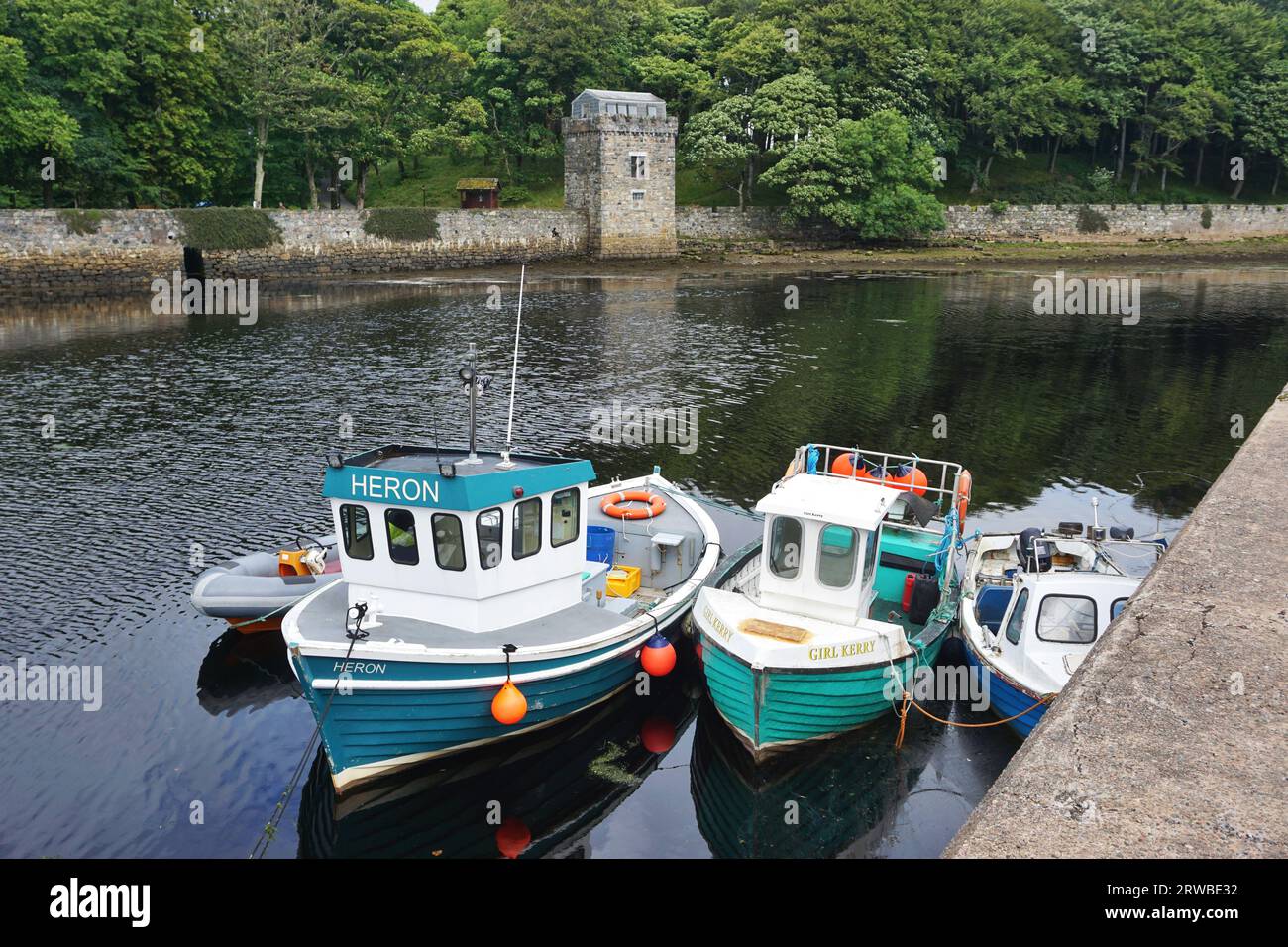 Colorful small boats share a moorage along the channel wall in the sheltered inner harbor at Stornoway, Isle of Lewis, Outer Hebrides, Scotland Stock Photo