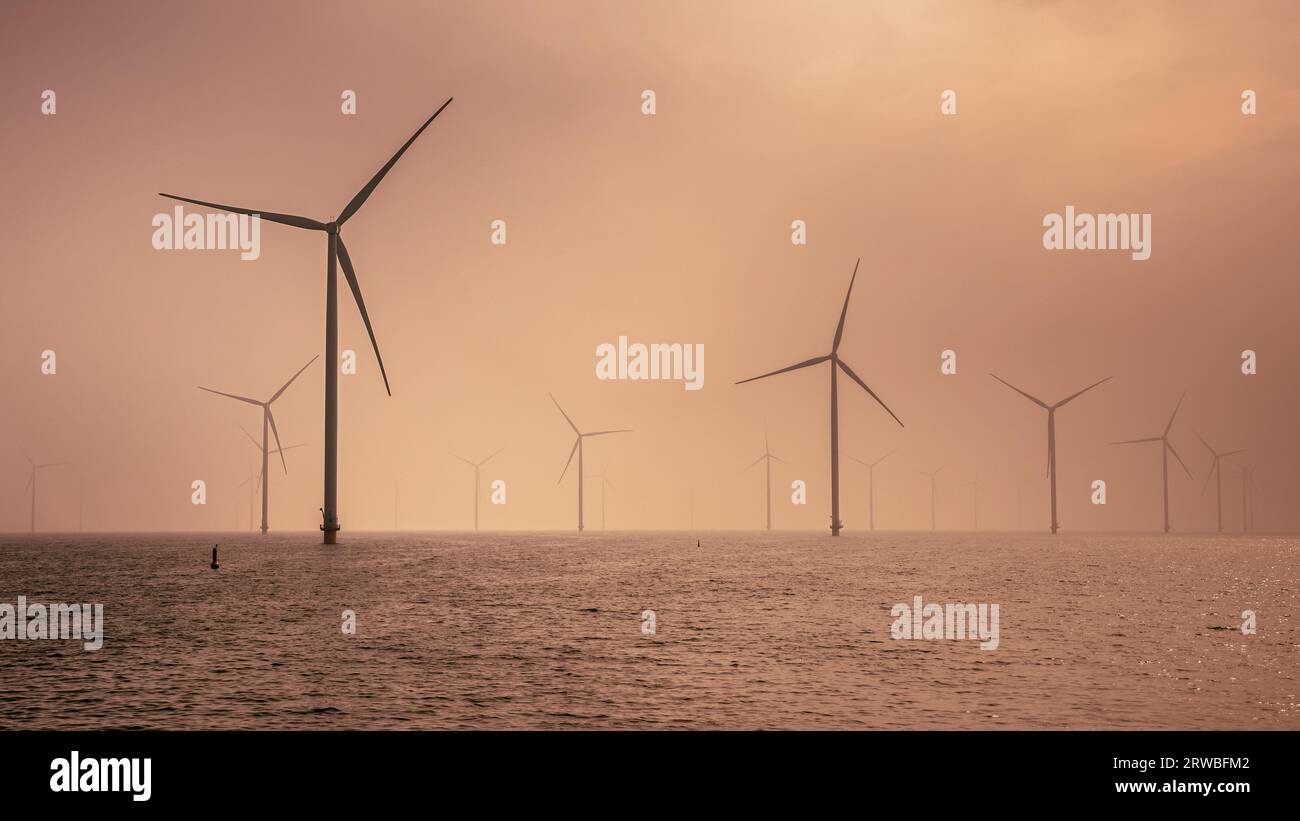 Wind Turbines and lake under a cloudy blue sky Stock Photo - Alamy