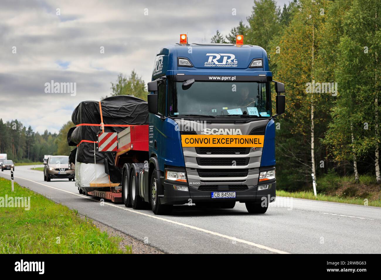 Scania R500 truck low loader trailer hauls tarpaulin covered object as oversize load in highway 25 traffic. Raasepori, Finland. September 8, 2023. Stock Photo