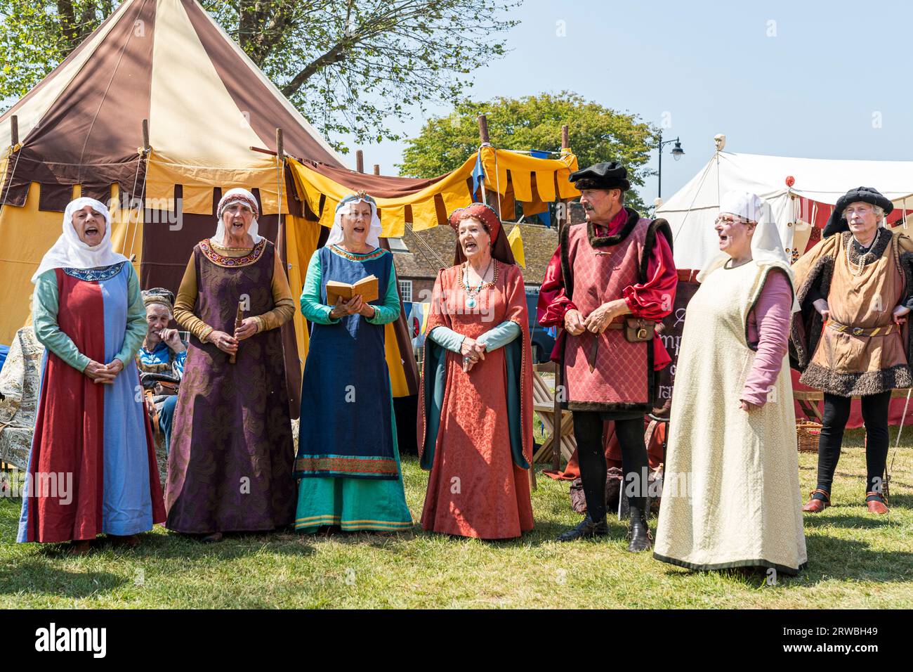The Rough Musicke medieval group of troubadours in a line singing in front of a middles ages tent at a reenactment event during the summertime. Stock Photo