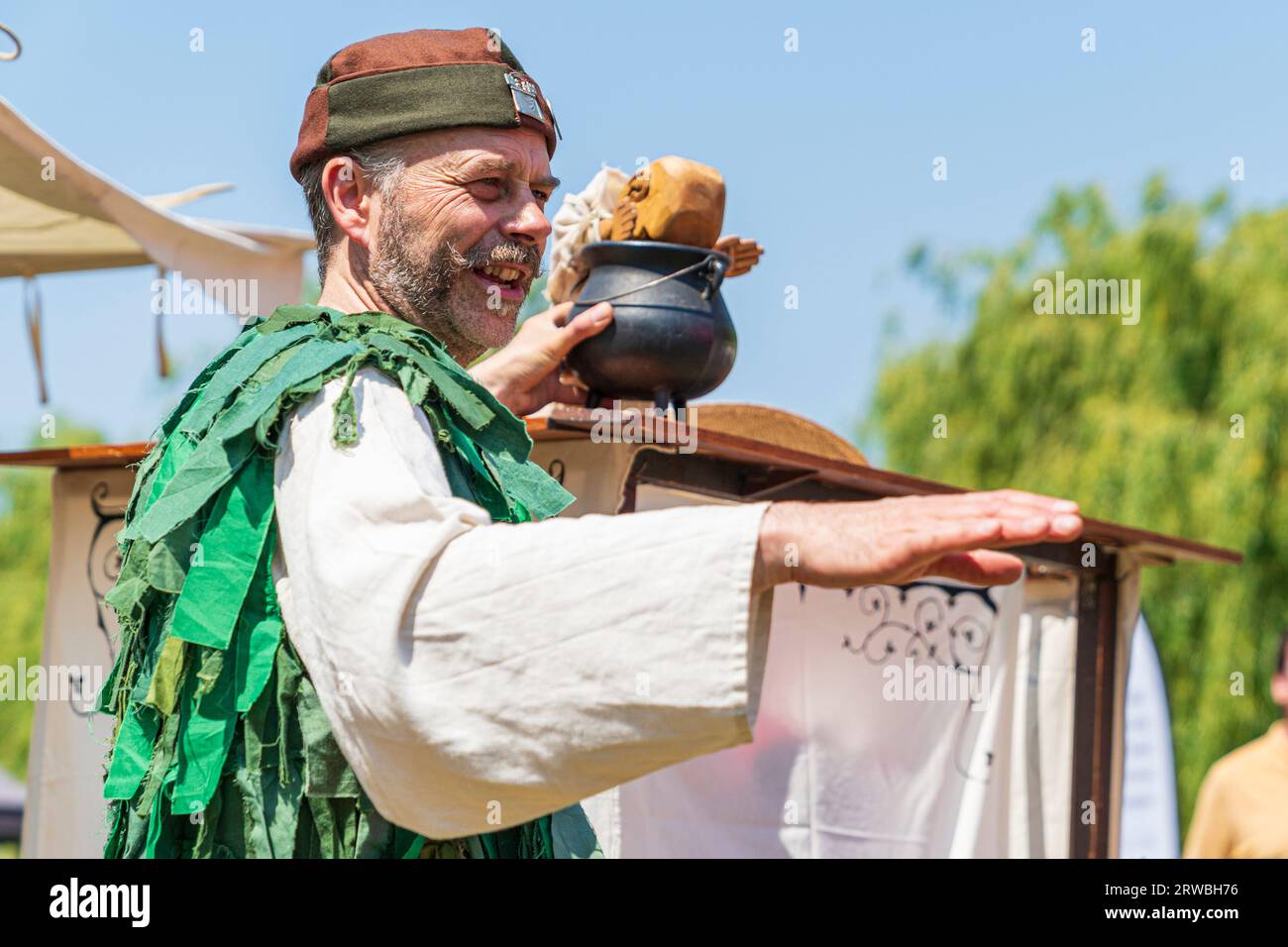 Medieval puppeteer in a green period costume, performing with puppet during a reenactment event at Sandwich town in kent in the summertime. Stock Photo