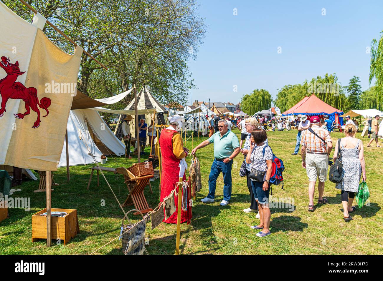 Wide angle shot of a medieval encampment during an event at Sandwich town in kent. visitors talking to a lady in period costume in the bright sunshine Stock Photo