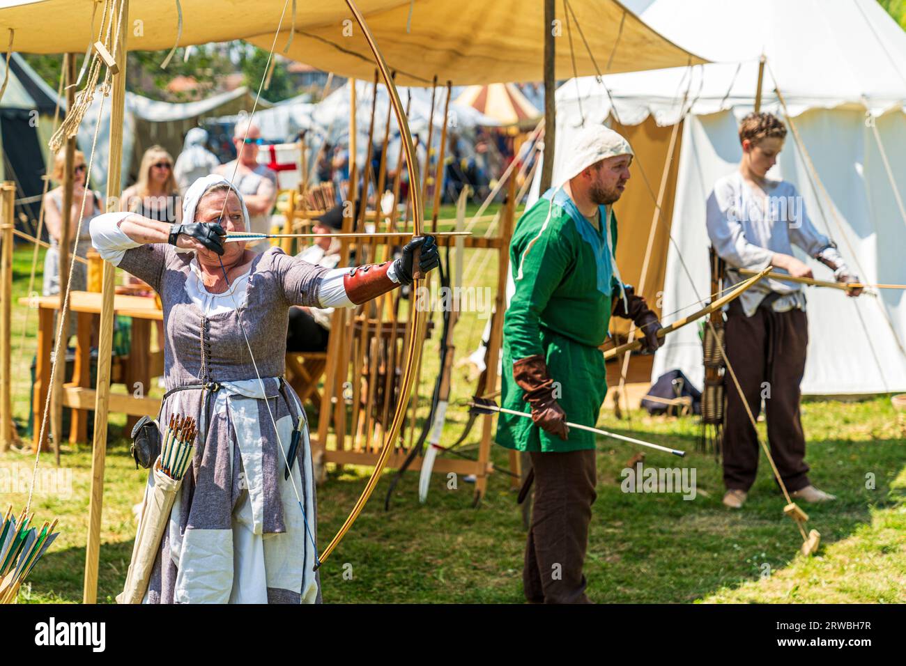 Medieval reenactment with a woman in period costume, aiming a bow and ...