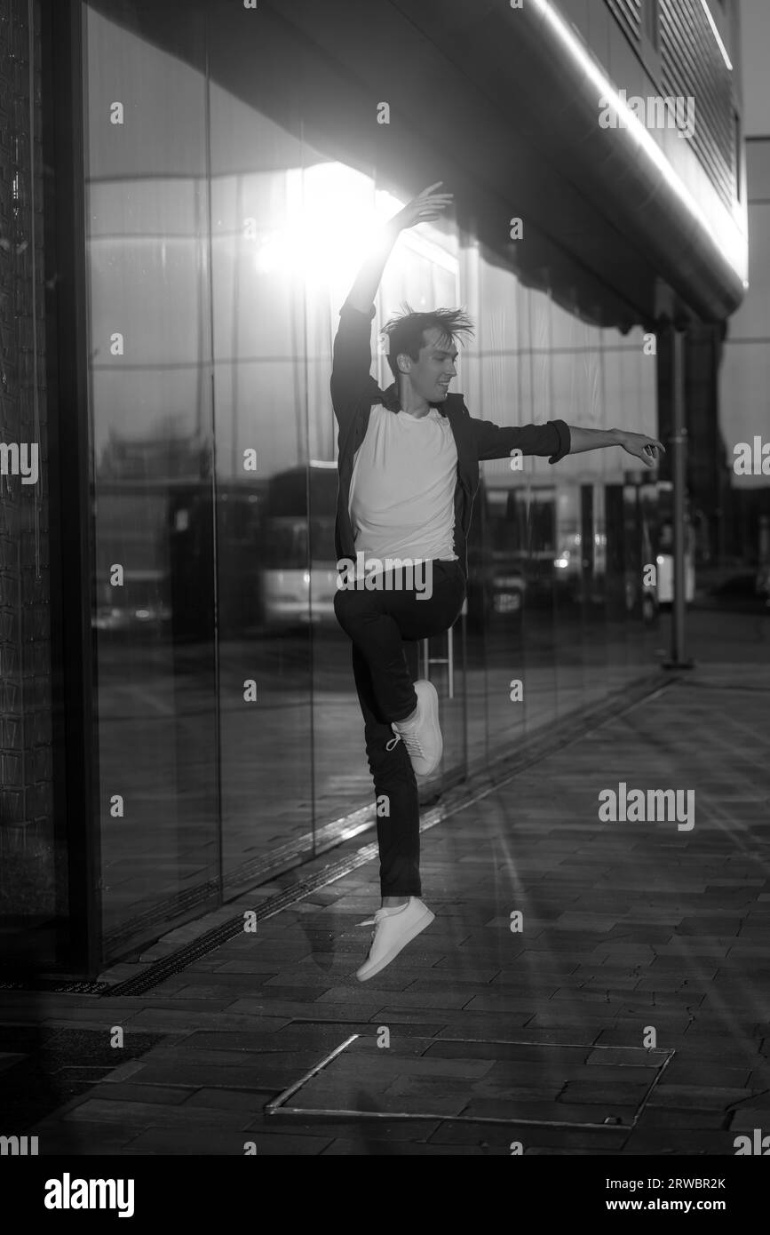 young attractive dancer in casual cloth doing ballet jump on the urban background. Contemporary dance, modern choreography. Stock Photo