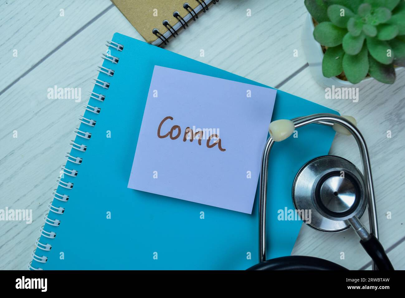 Concept of Coma write on sticky notes with stethoscope isolated on Wooden Table. Stock Photo