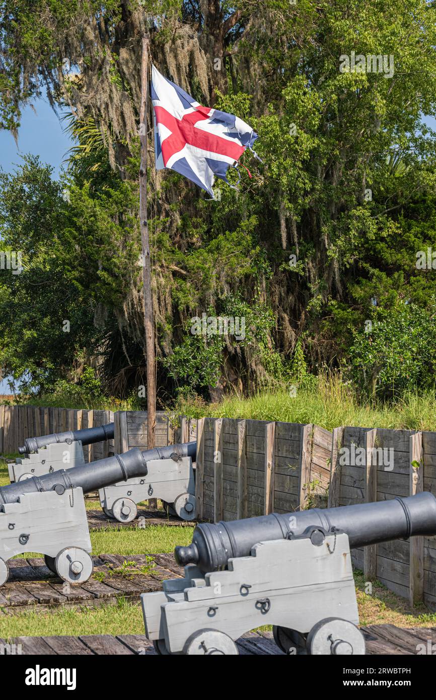 Tattered British flag waving above cannons at the reconstructed 18th century Fort King George on the Altamaha River in Darien, Georgia. (USA) Stock Photo