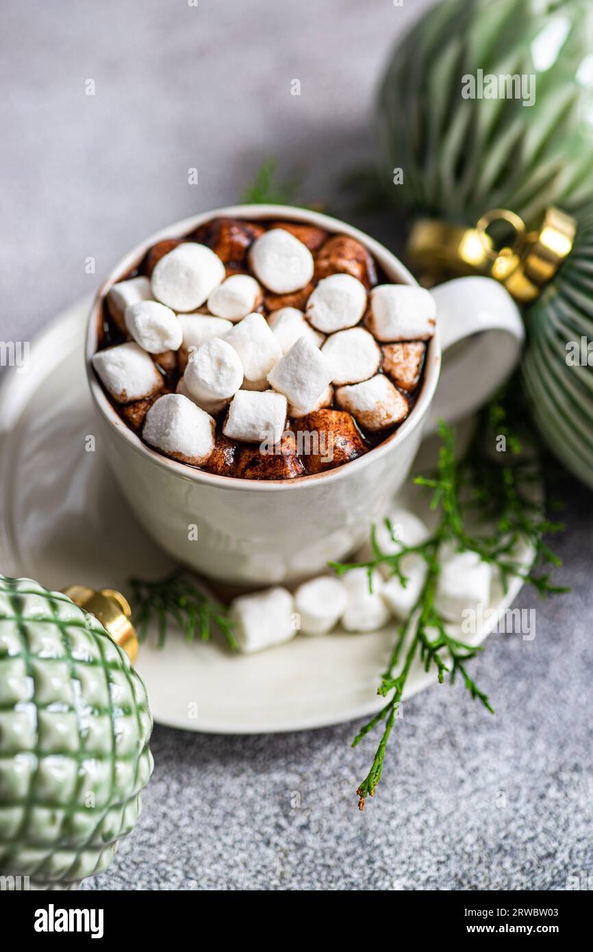 Top view of delicious cocoa with marshmallow on plate with fir twigs placed near Christmas balls Stock Photo