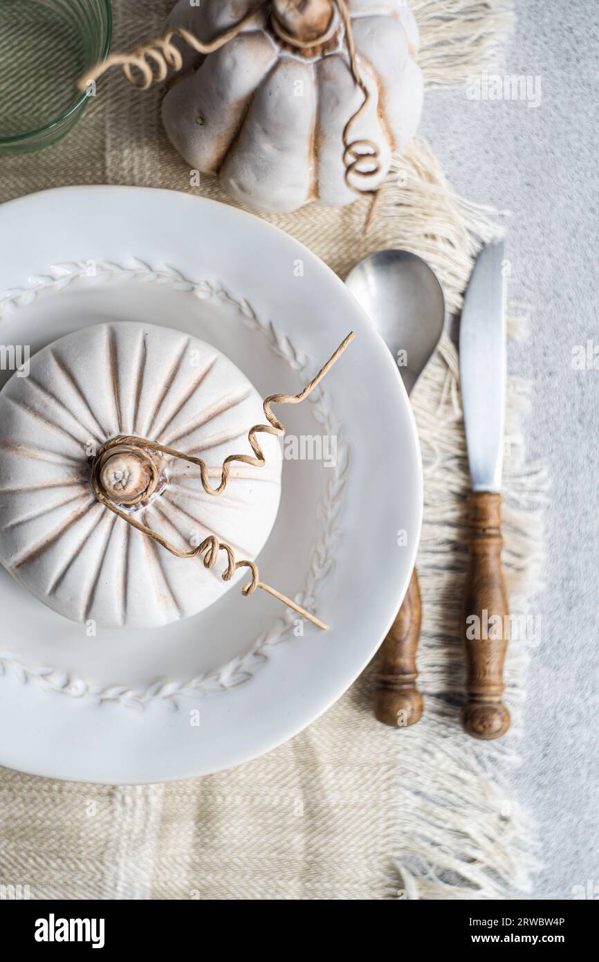 Top view of autumnal table setting with white pumpkin on plate placed on table near cutlery and glass Stock Photo