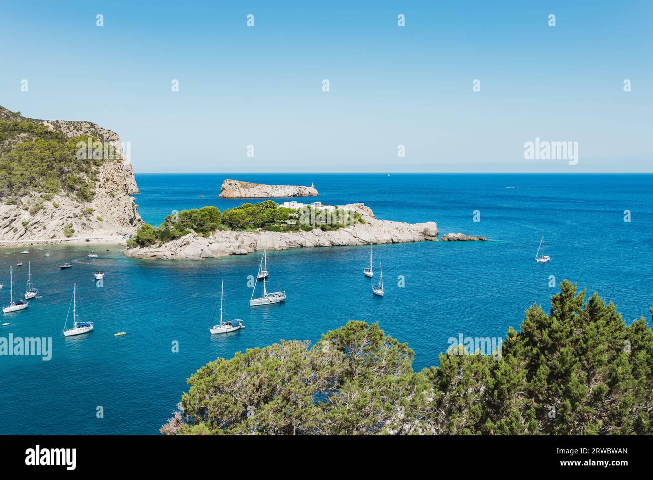 Picturesque scenery of turquoise sea with boats sailing and green mountains in Balearic Islands (Ibiza) Spain in sunny day Stock Photo