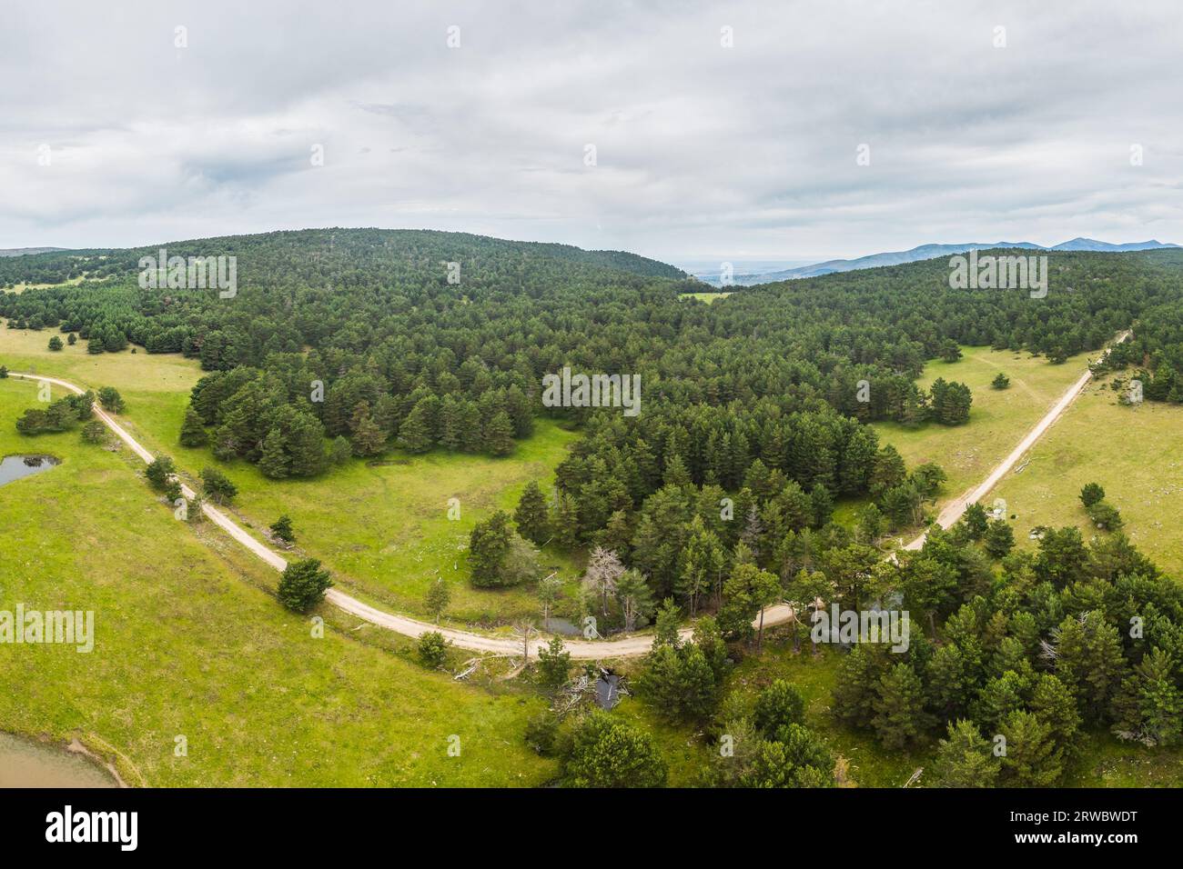 Aerial view of asphalt road going through green and hills covered with ...